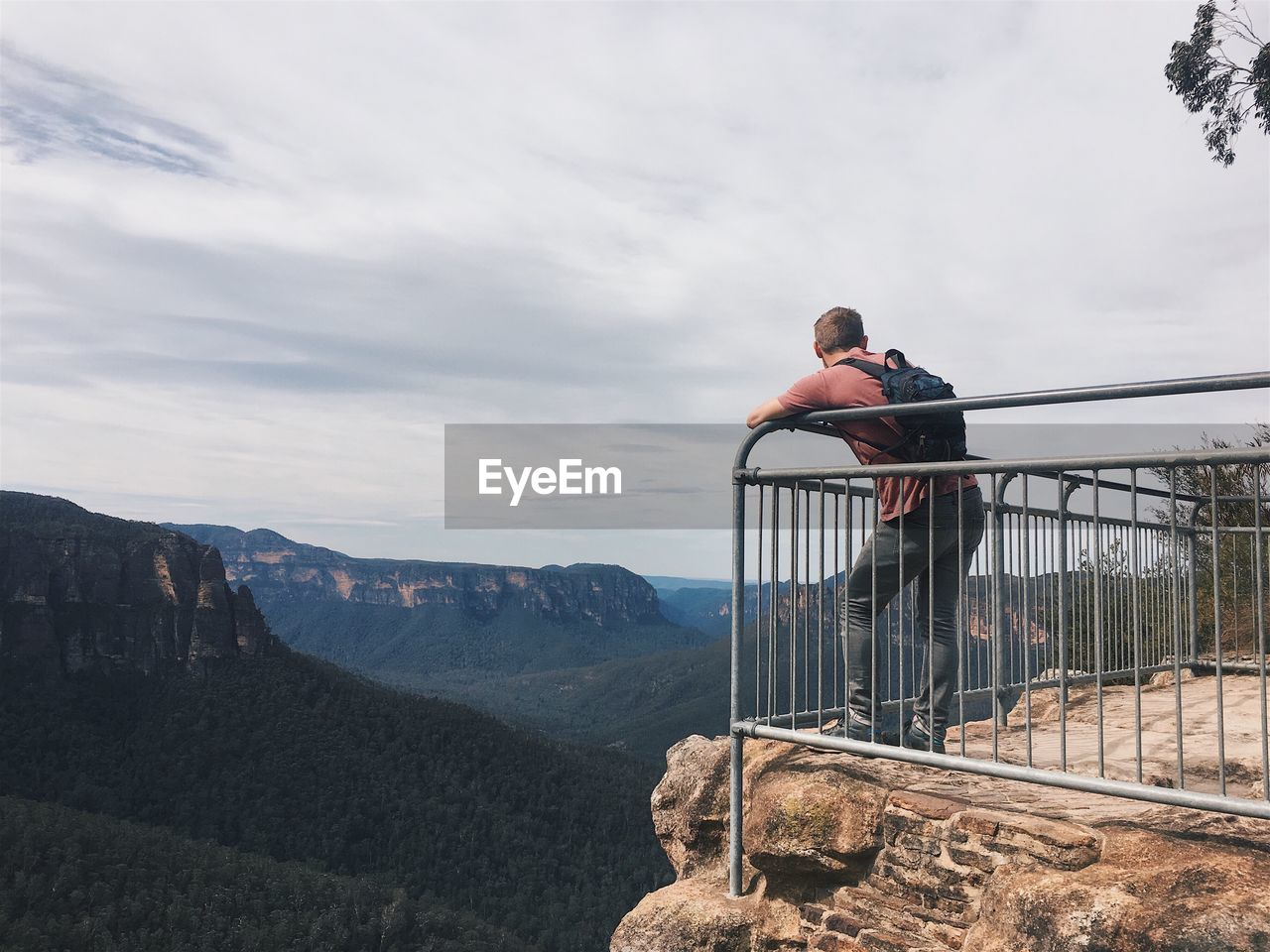 People standing by railing against mountains