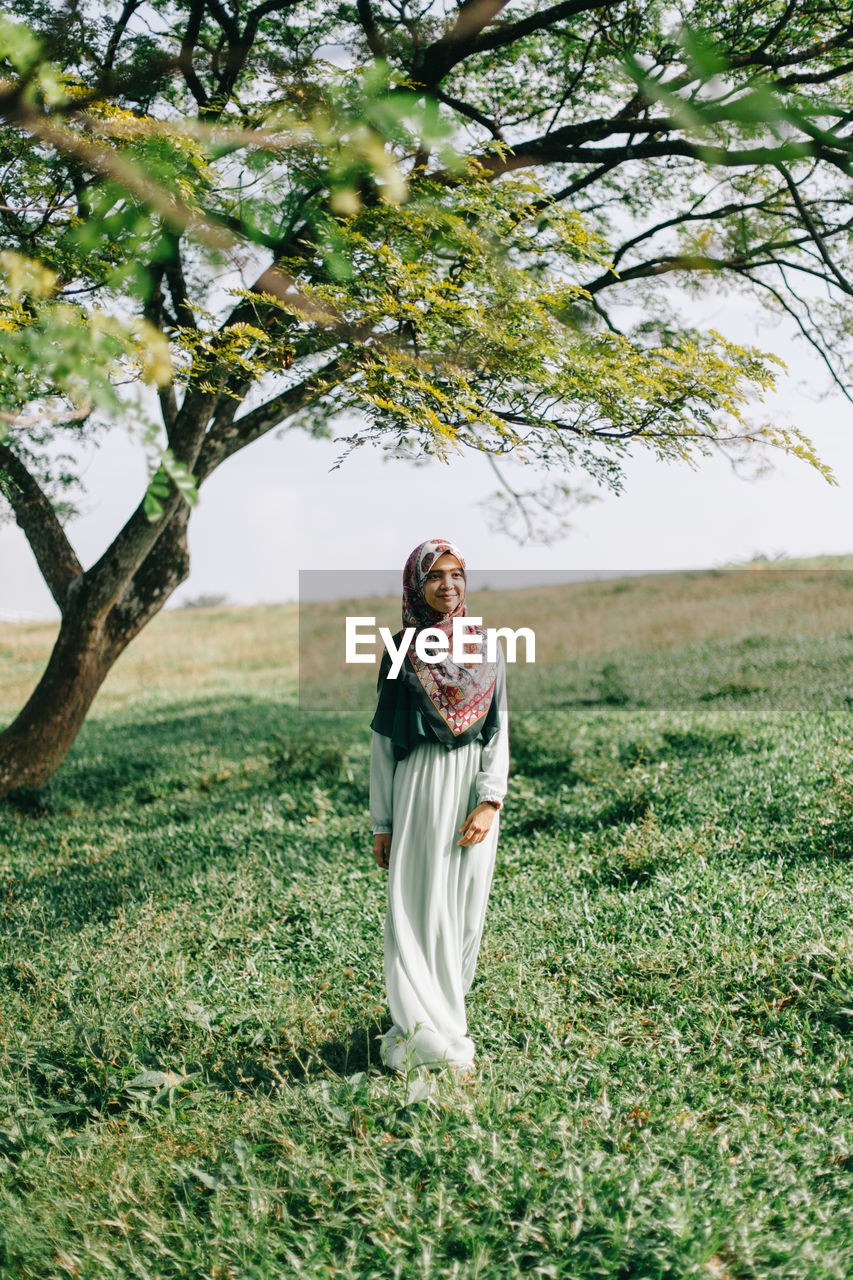 PORTRAIT OF YOUNG WOMAN WITH UMBRELLA ON TREE