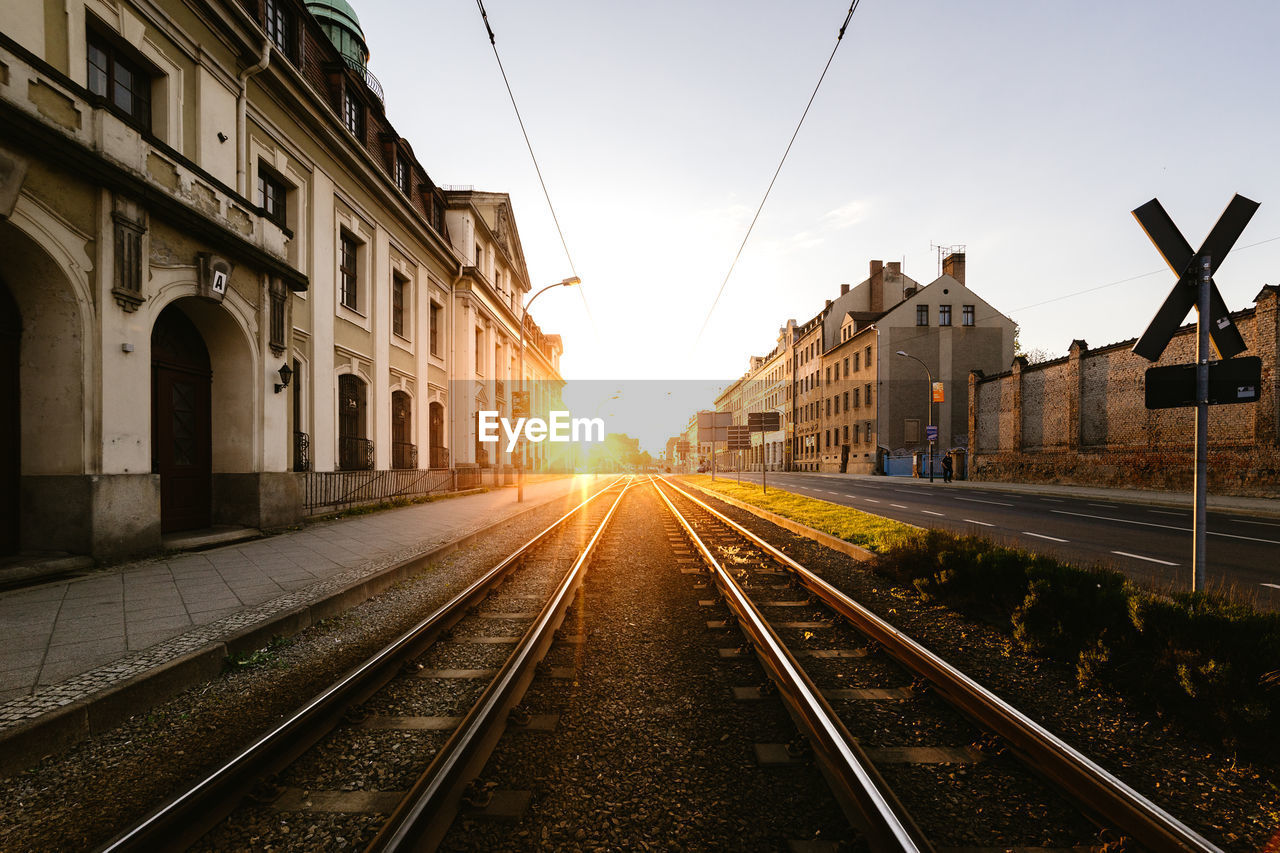 Railroad tracks against sky during sunset in city