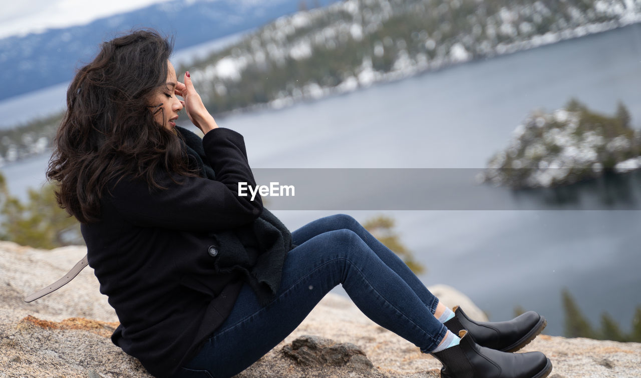 Young woman with eyes closed sitting on rock