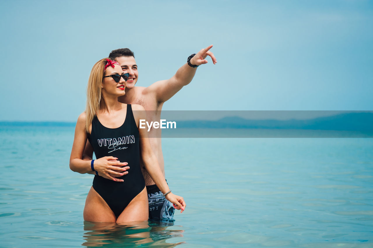 Young couple spending leisure time at beach against sky