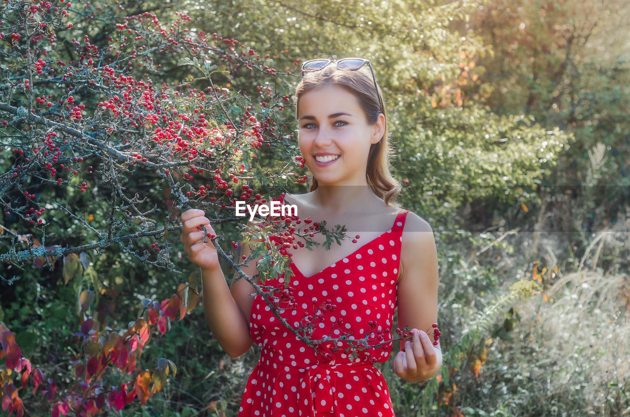 Young woman near bush with red hawthorn berries. smile, natural beauty