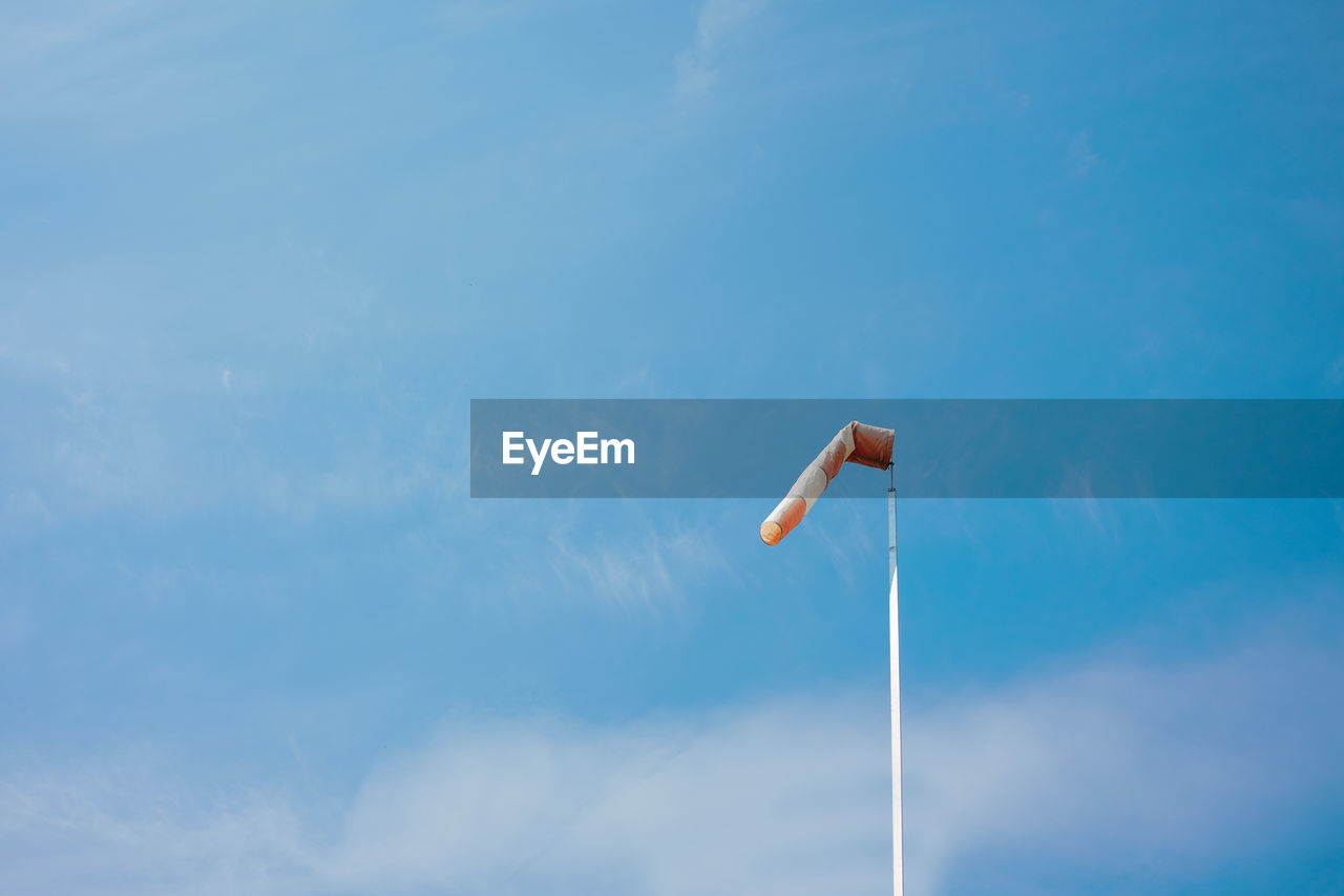 Red white striped wind sock in front of blue sky