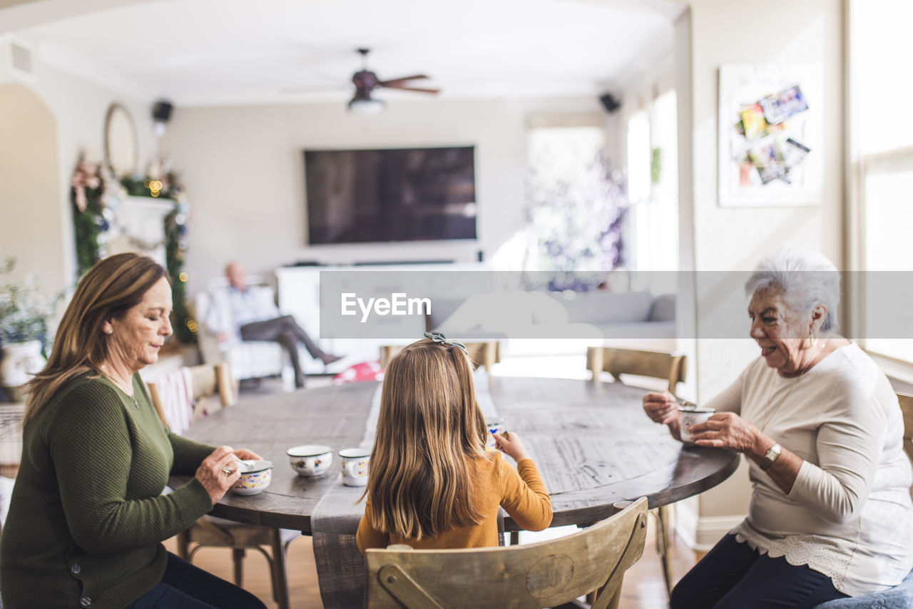 Multigenerational family playing with tea set at kitchen table