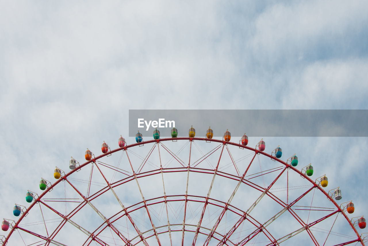 Low angle view of ferris wheel against cloudy sky