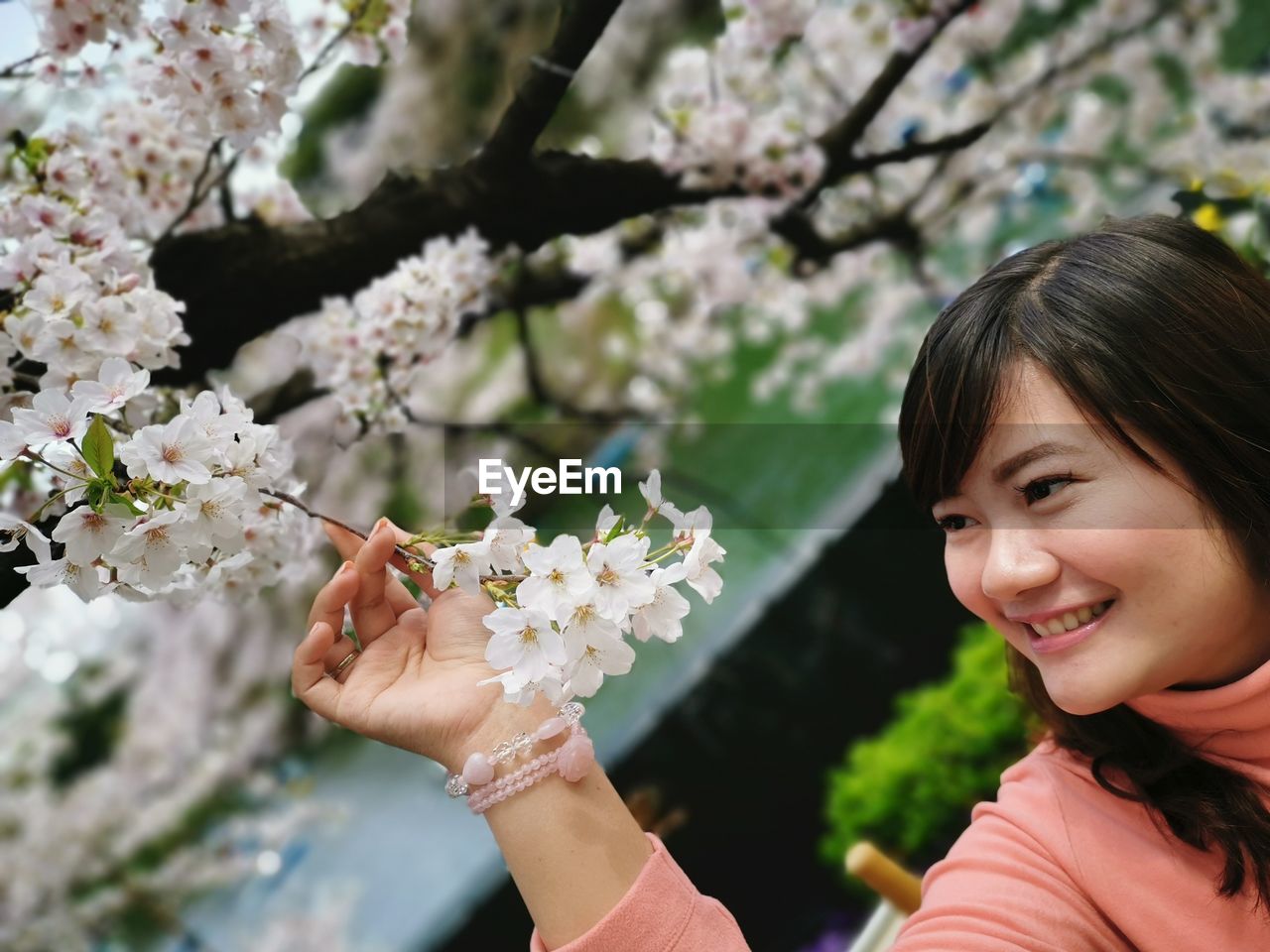 Smiling young woman looking at white flowers