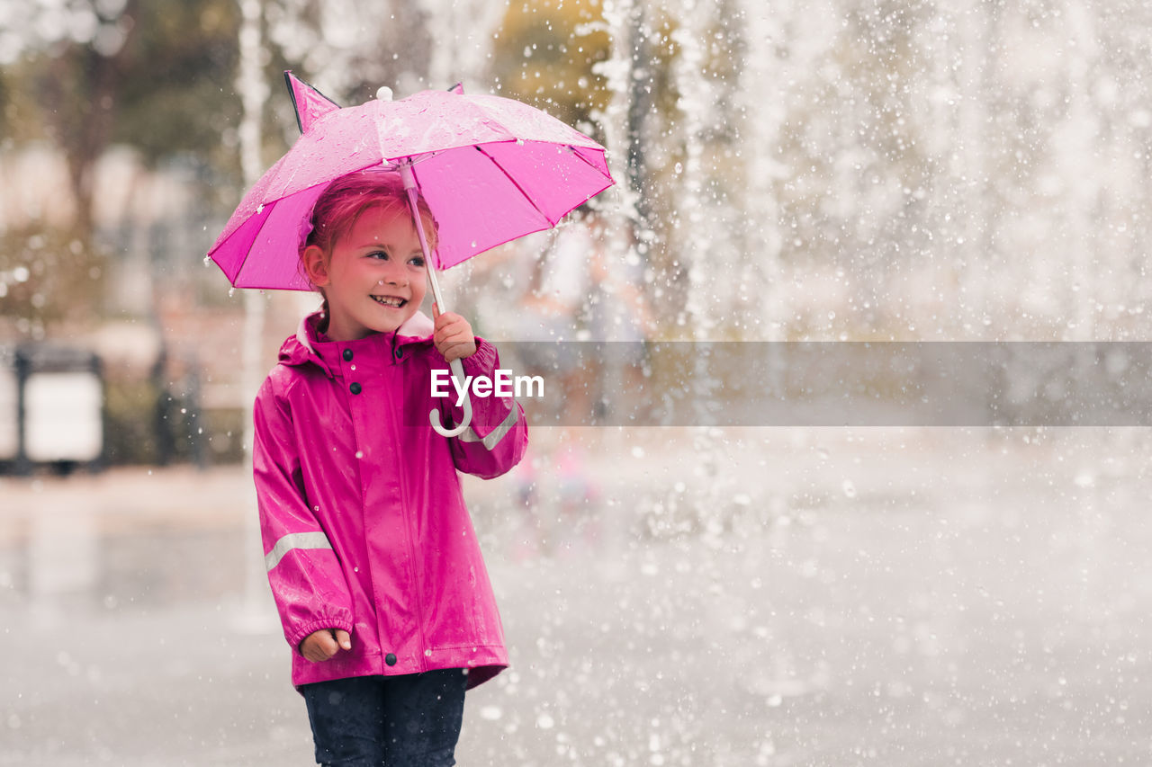 Cute girl holding umbrella in rain