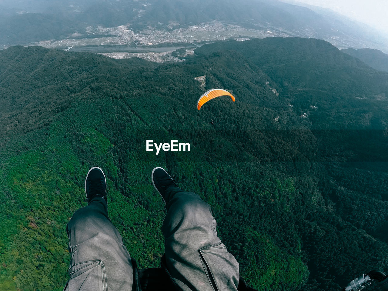LOW SECTION OF MAN PARAGLIDING OVER MOUNTAINS