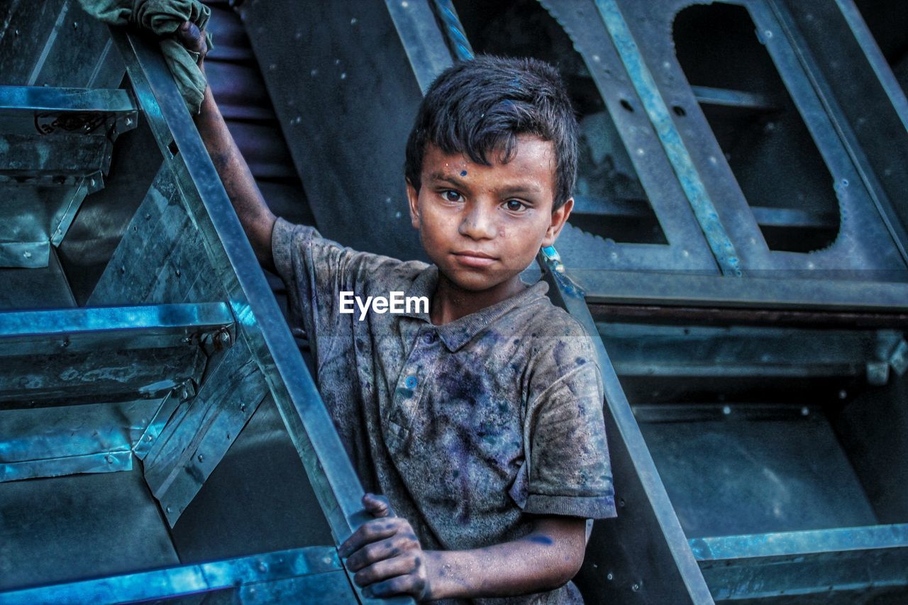 PORTRAIT OF BOY STANDING AGAINST STAIRCASE