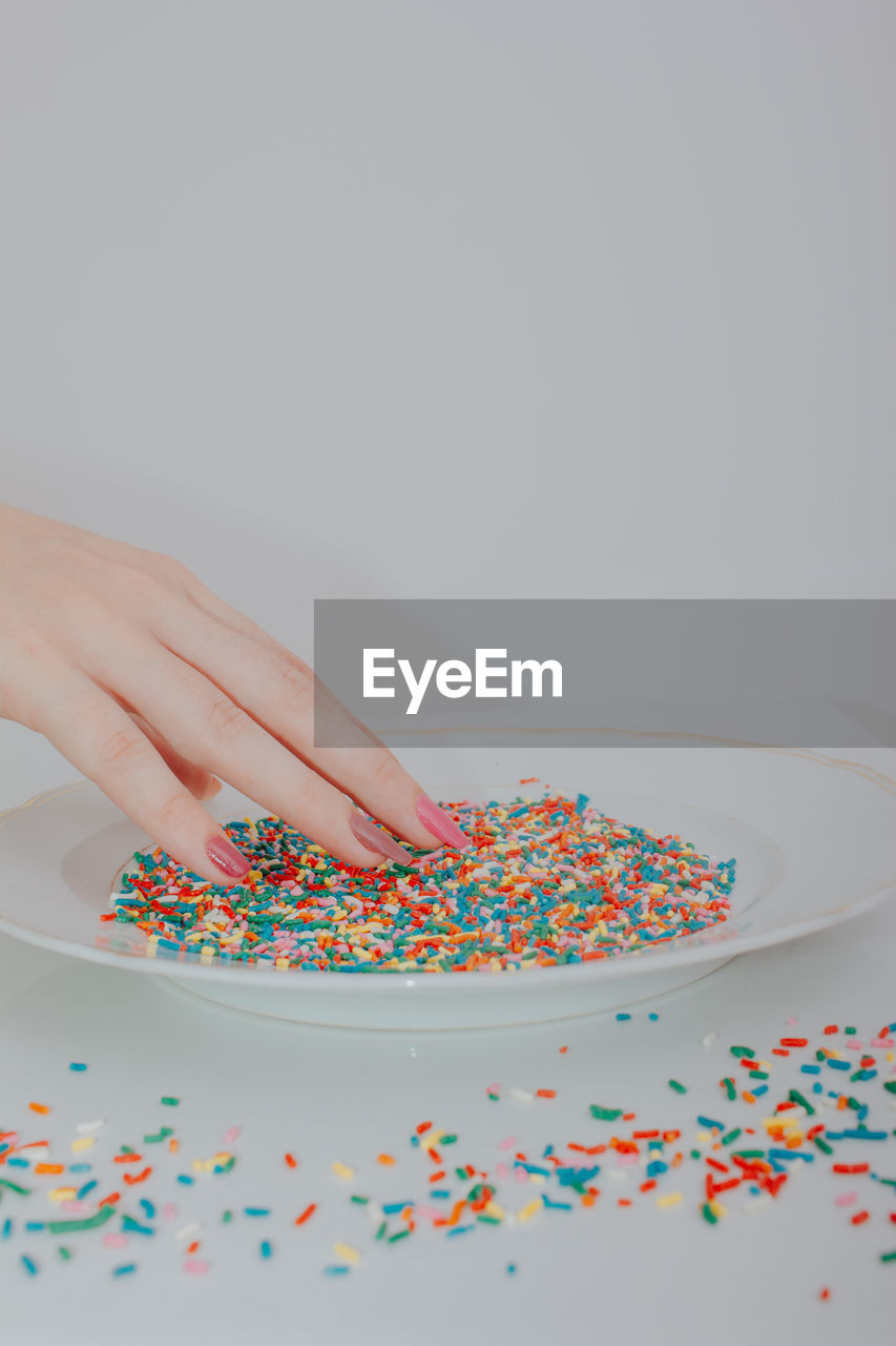 Hands holding plate full of colorful confetti