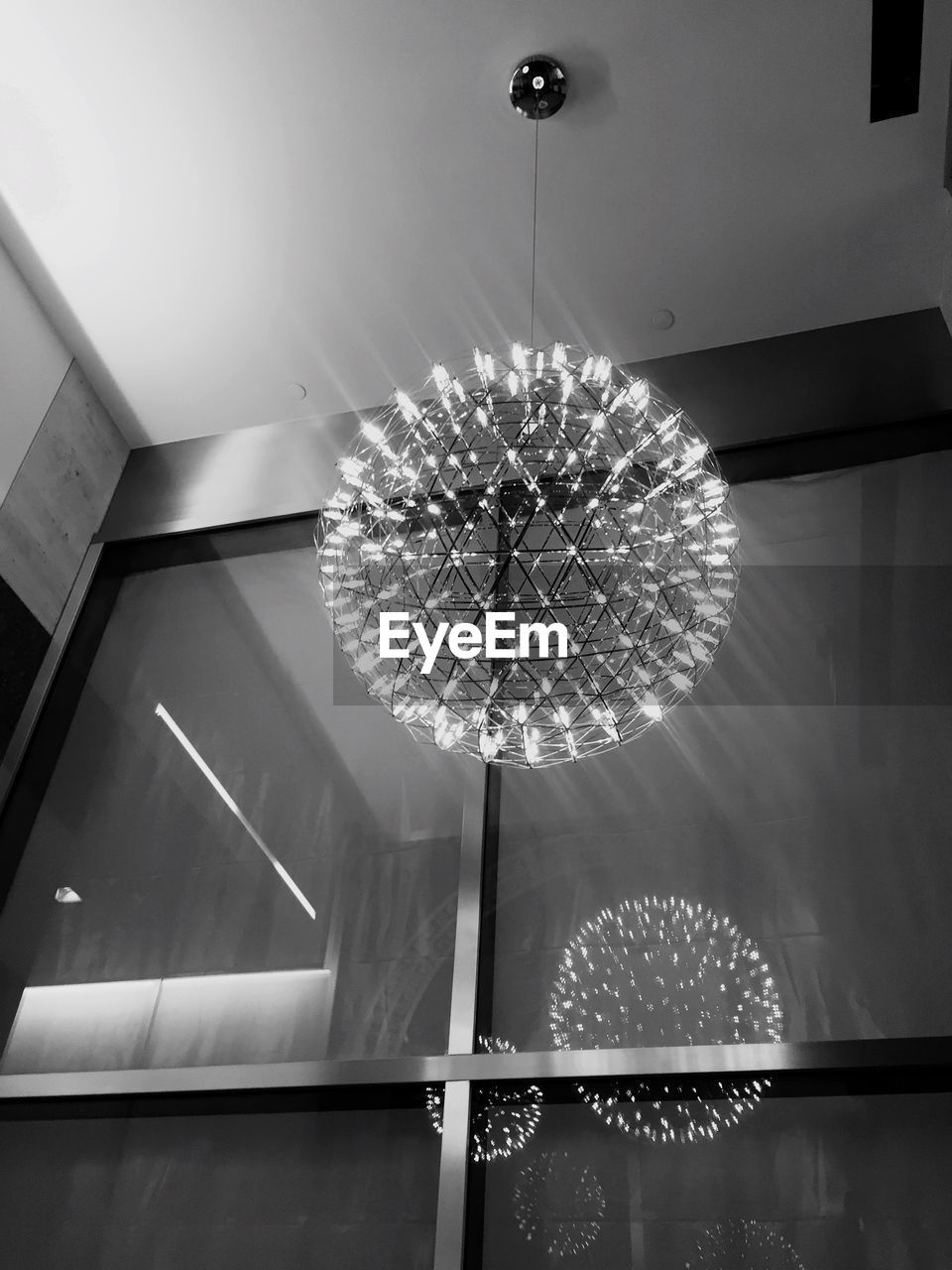 LOW ANGLE VIEW OF ILLUMINATED CHANDELIER HANGING FROM CEILING