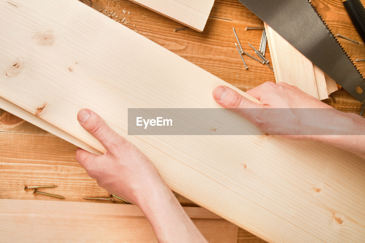 Cropped hands of carpenter holding plank in workshop
