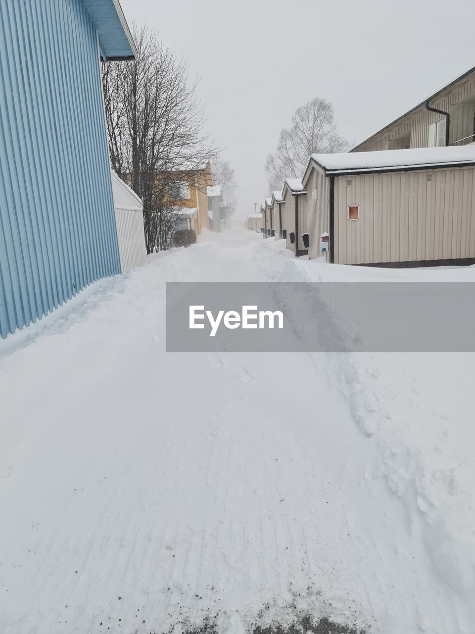 SNOW COVERED HOUSES AMIDST BUILDINGS AGAINST SKY