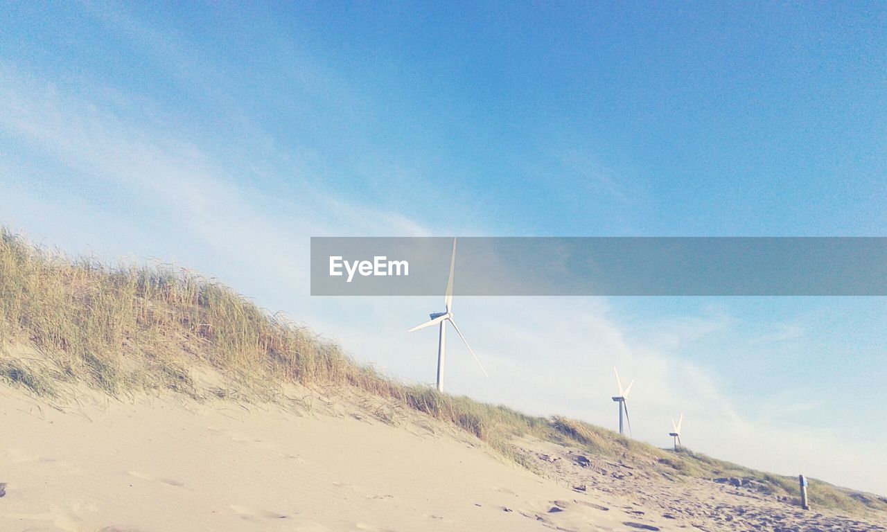 Windmill on beach against sky