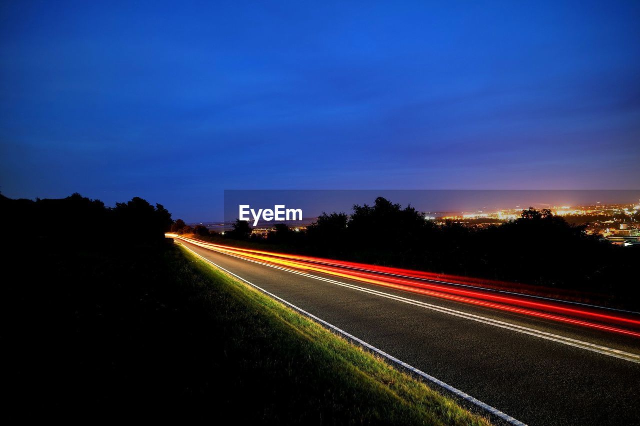 Light trails on road against sky at night