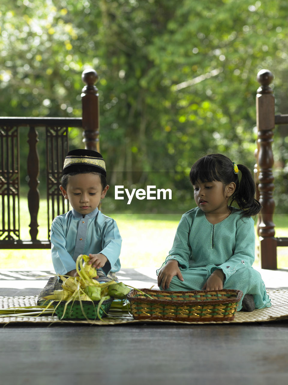 Children in traditional clothing sitting on mat