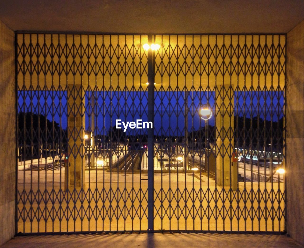 Closed gate of illuminated building against sky