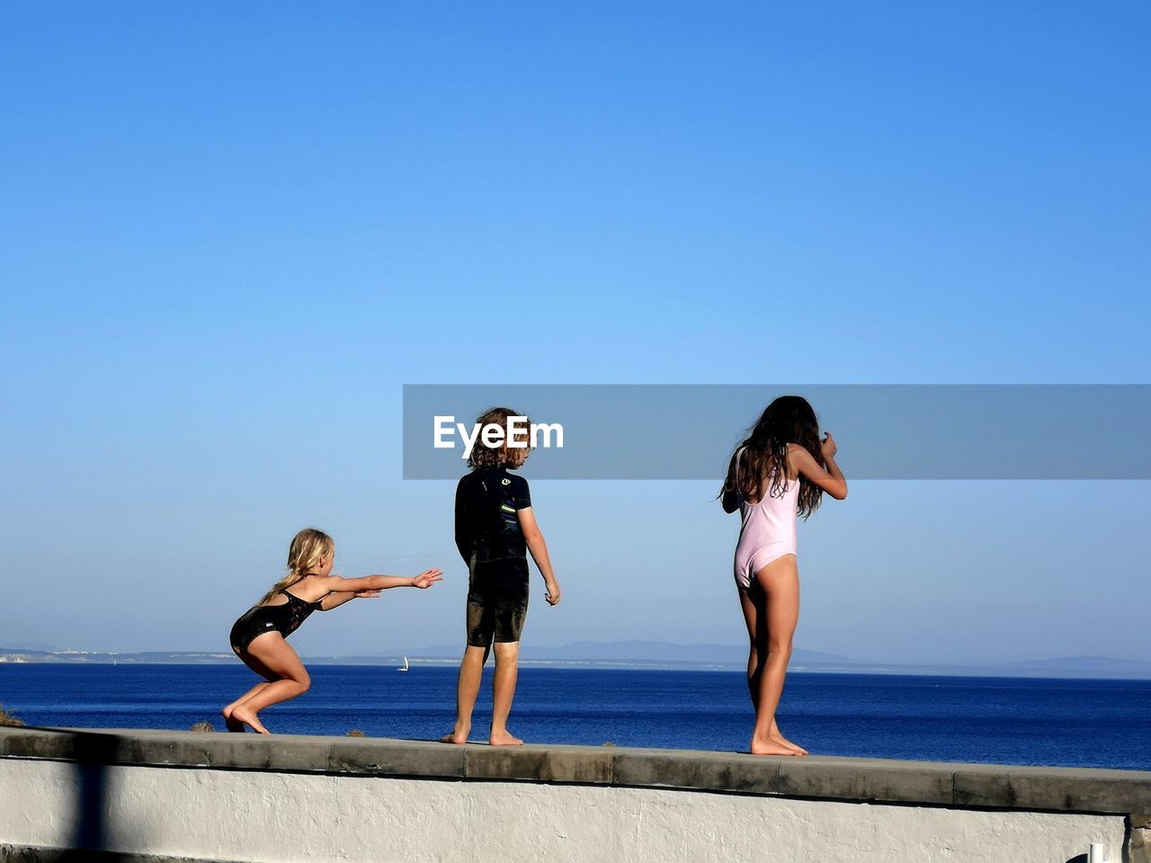 REAR VIEW OF WOMEN AGAINST SEA