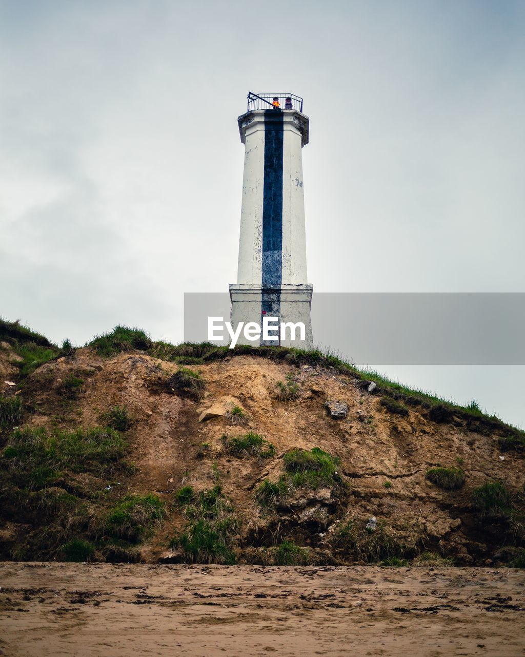 LOW ANGLE VIEW OF LIGHTHOUSE AMIDST BUILDING AGAINST SKY