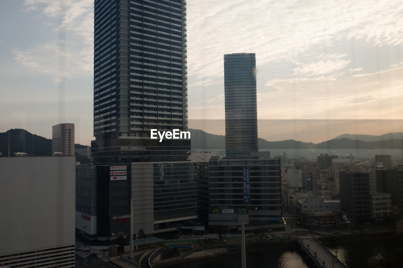 Modern cityscape against sky during sunset