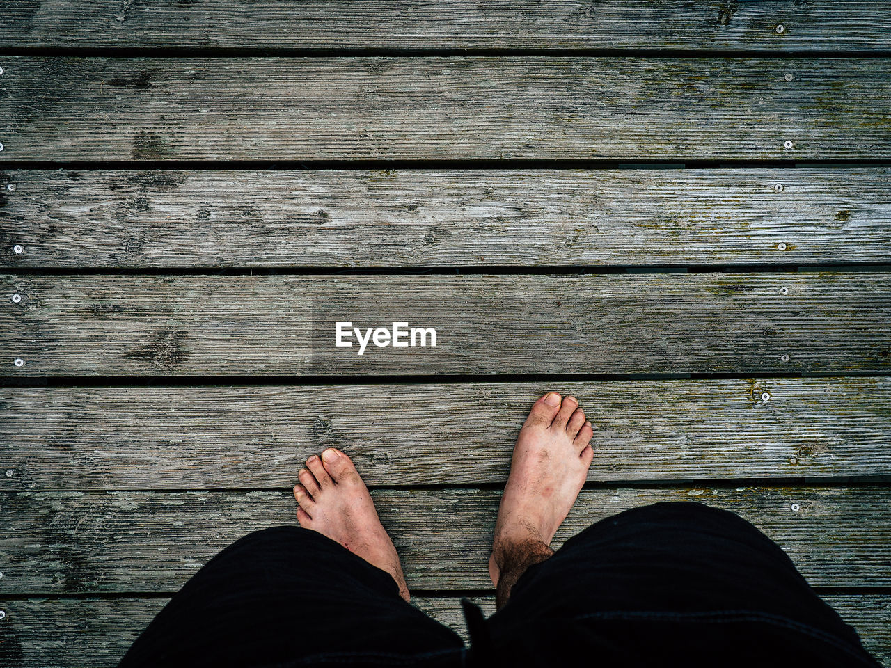 Low section of man standing on boardwalk