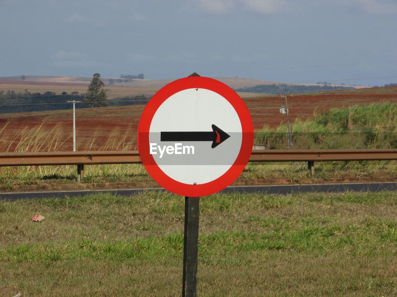 Road sign on field against sky