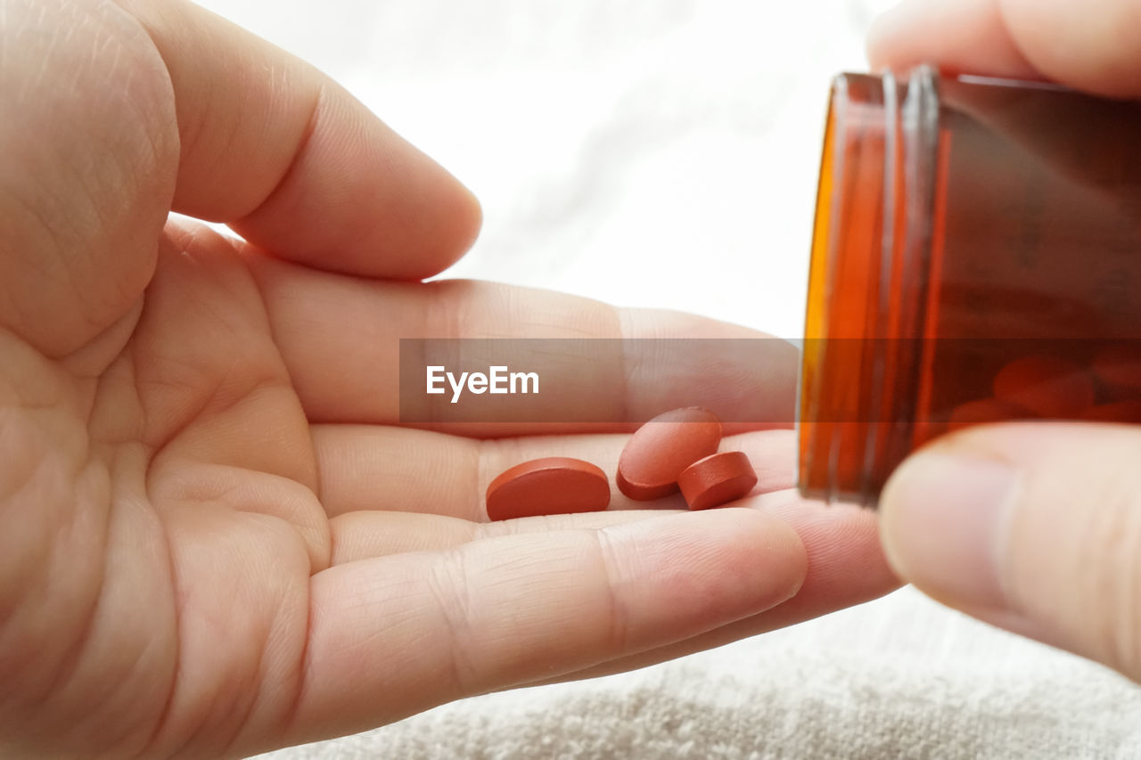 Close-up of hands taking medicines at table