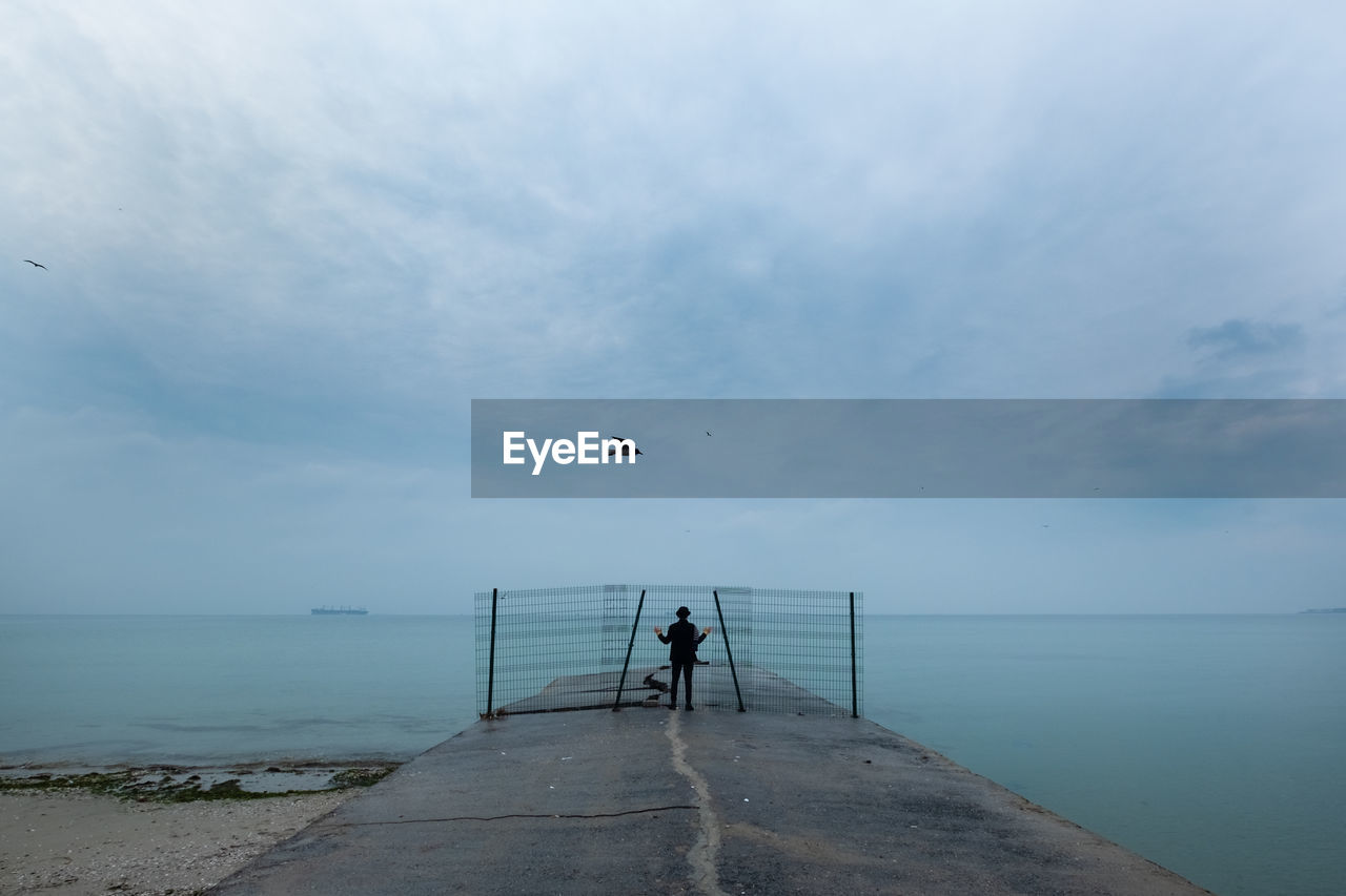 Woman standing behind bars near the sea