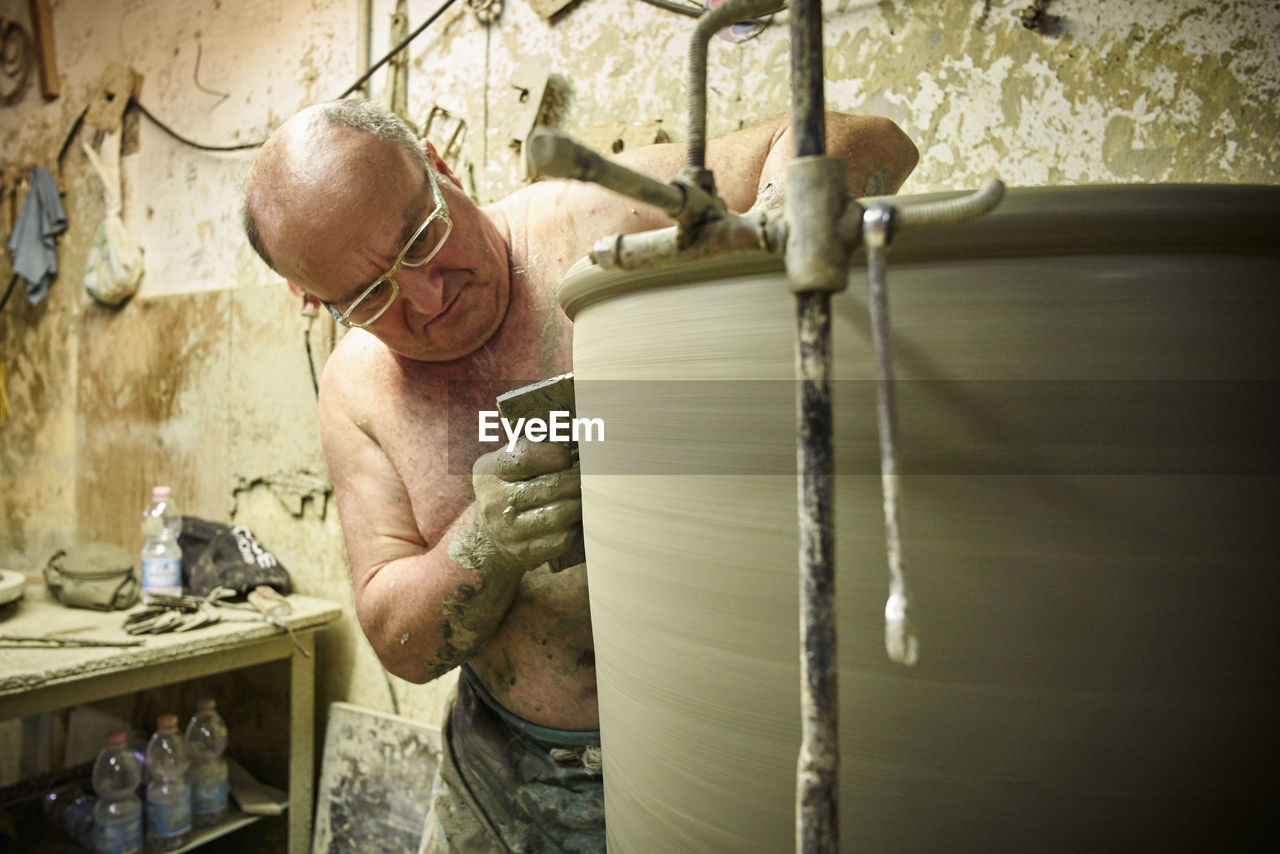 Potter in workshop working on large terracotta vase