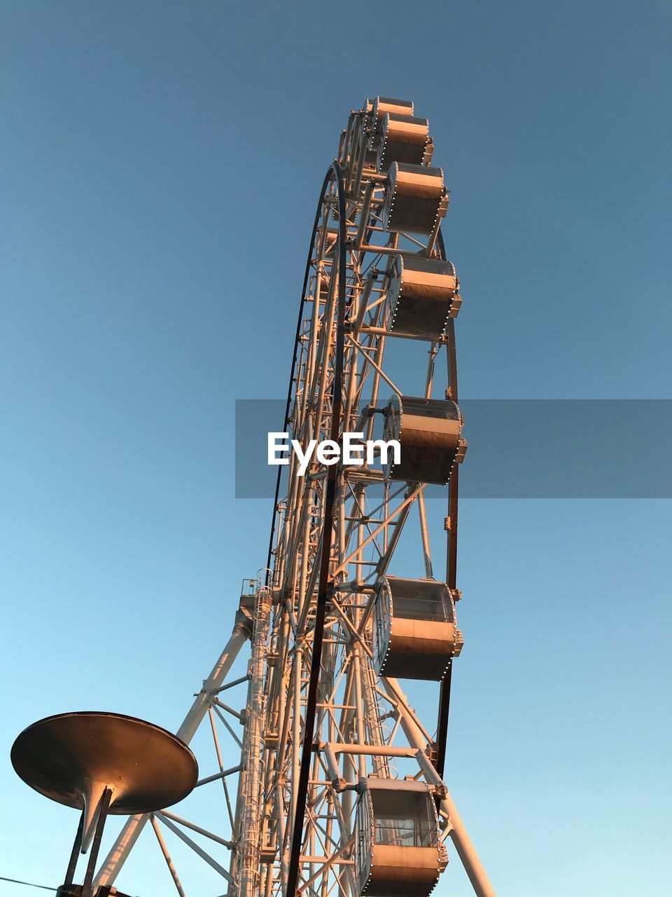 Low angle view of ferris wheel against clear blue sky