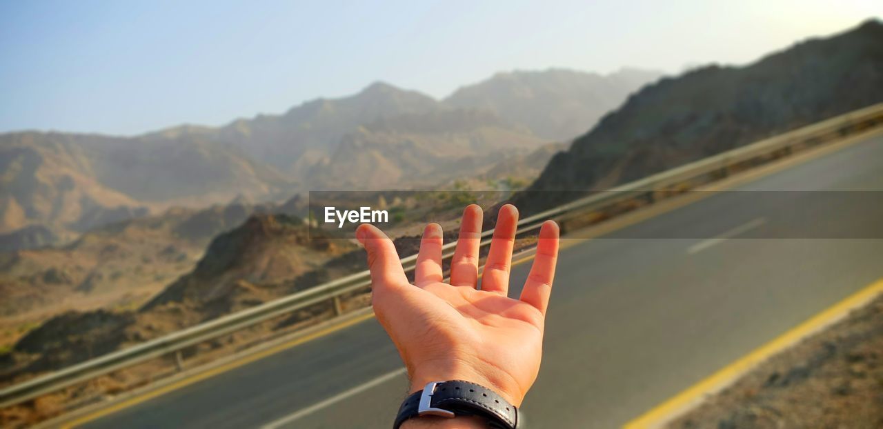 Close-up of hand against mountain