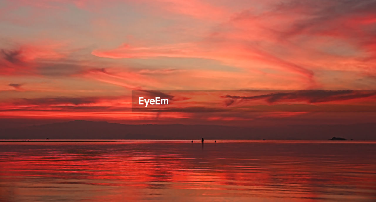 Scenic view of sea against dramatic sky during sunset