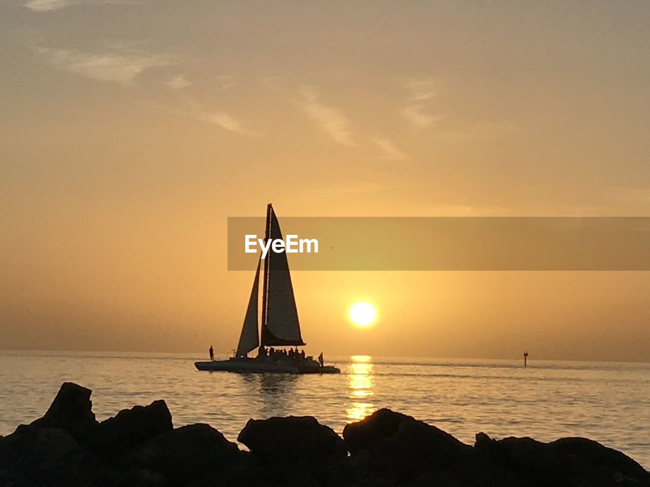 SAILBOAT SAILING IN SEA AGAINST SKY AT SUNSET