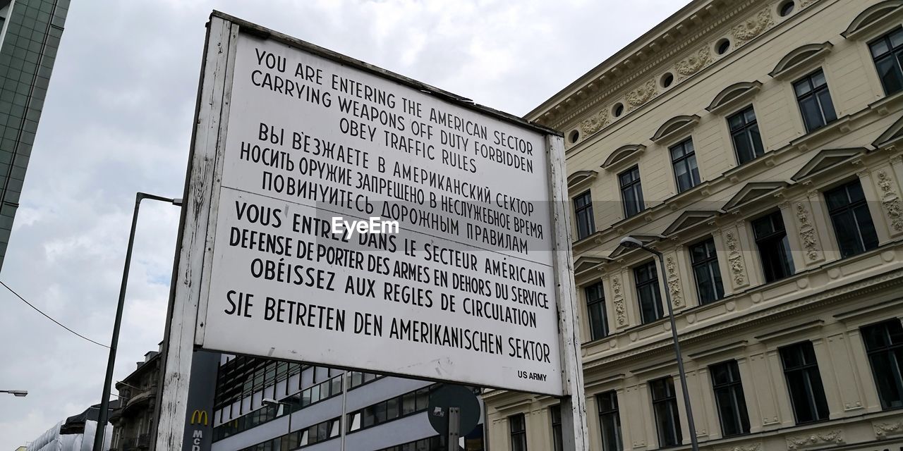 LOW ANGLE VIEW OF INFORMATION SIGN AGAINST SKY IN CITY