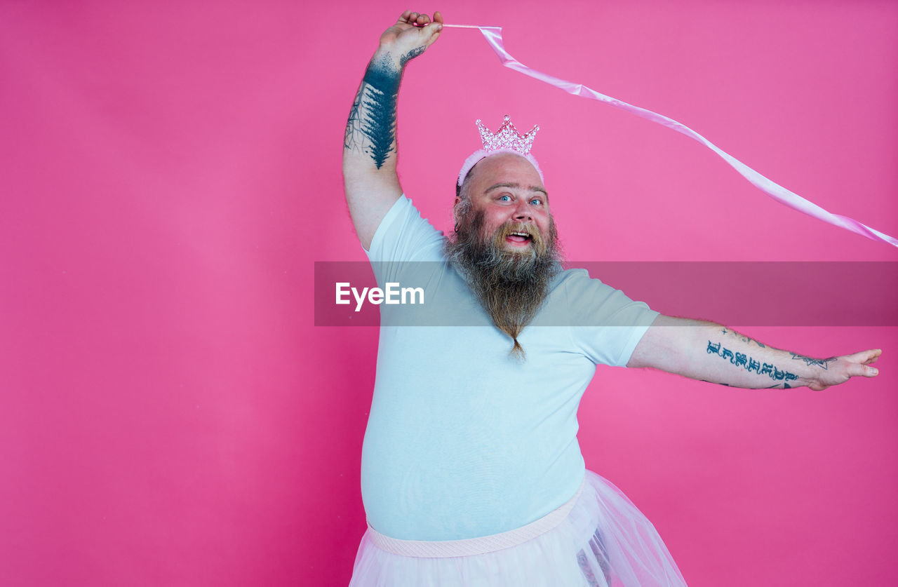Portrait of man dancing against pink background