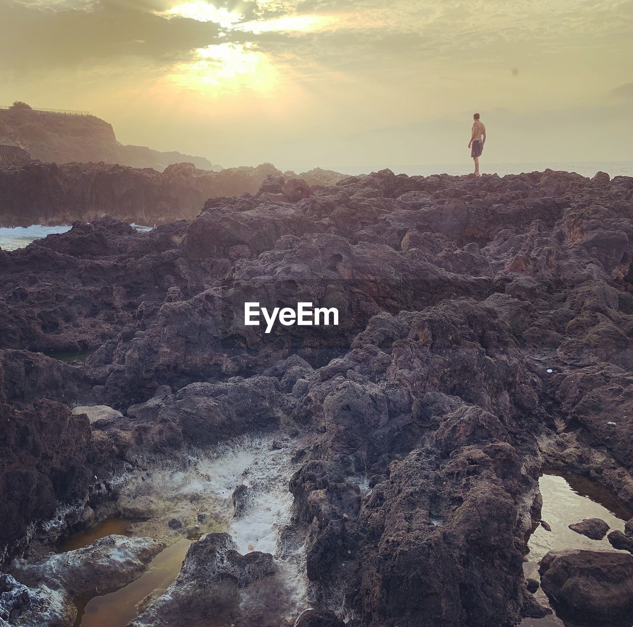 MAN STANDING ON ROCK AGAINST SKY