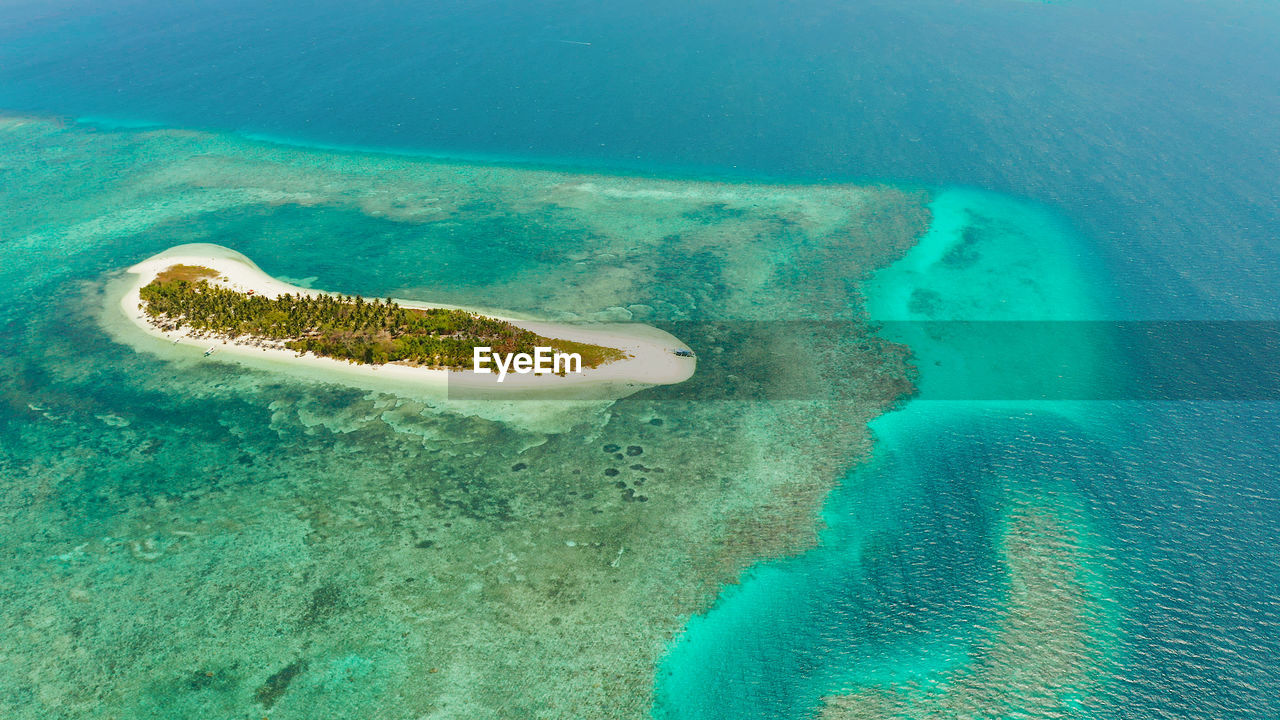 Tropical island on an atoll with beautiful sandy beach by coral reef from above. canimeran island 