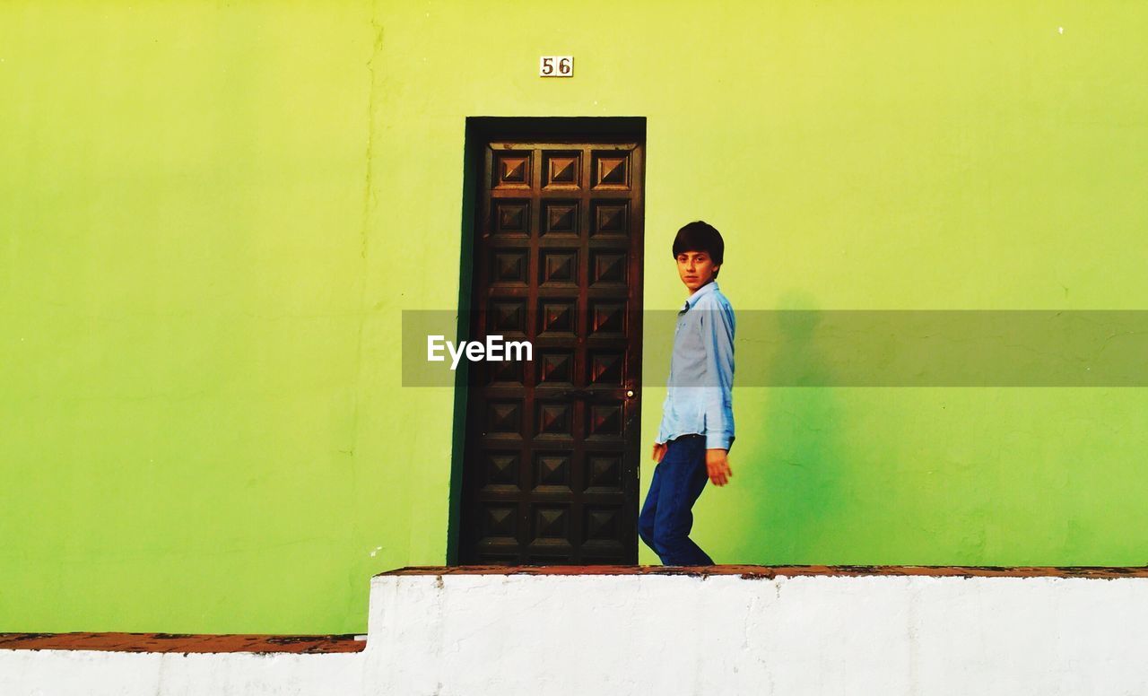 Teenage boy against green wall