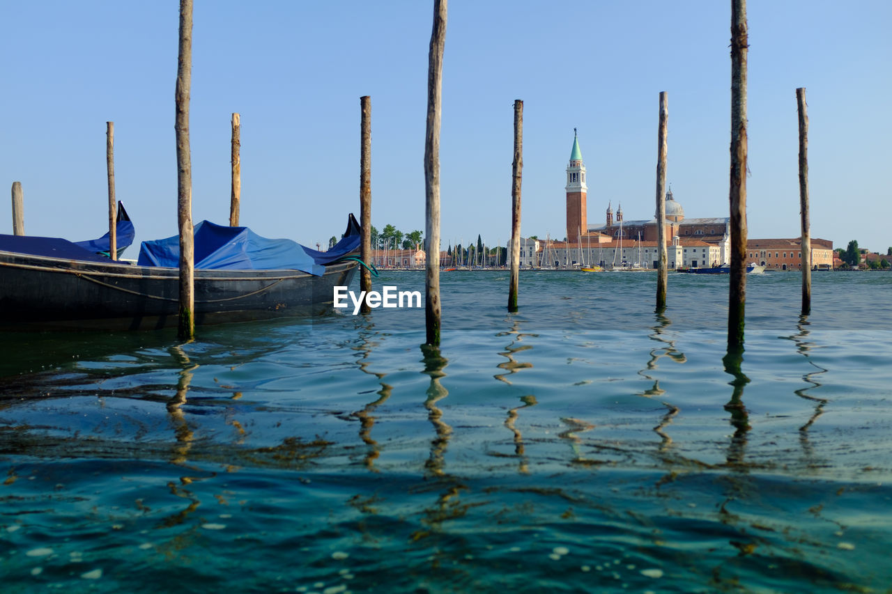 Wooden posts in sea with distant view of church of san giorgio maggiore against sky