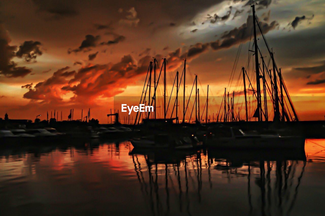 Silhouettes of sailing boats in marina during sunset