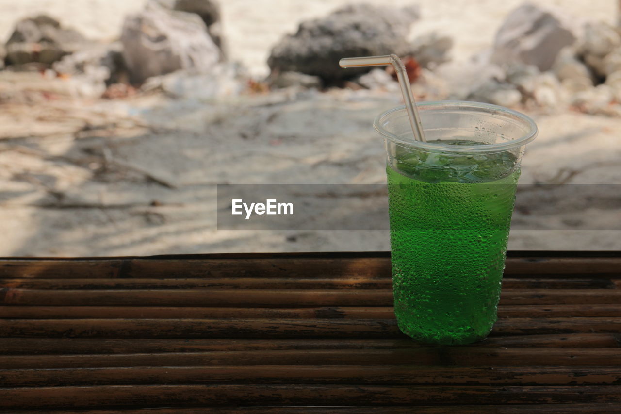 Sweet green drinking water in the cup on the beach