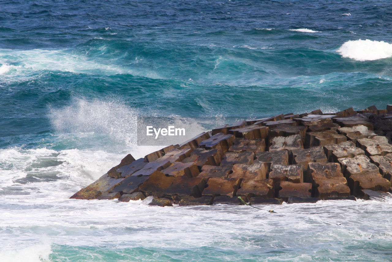 HIGH ANGLE VIEW OF WAVES BREAKING ON SHORE