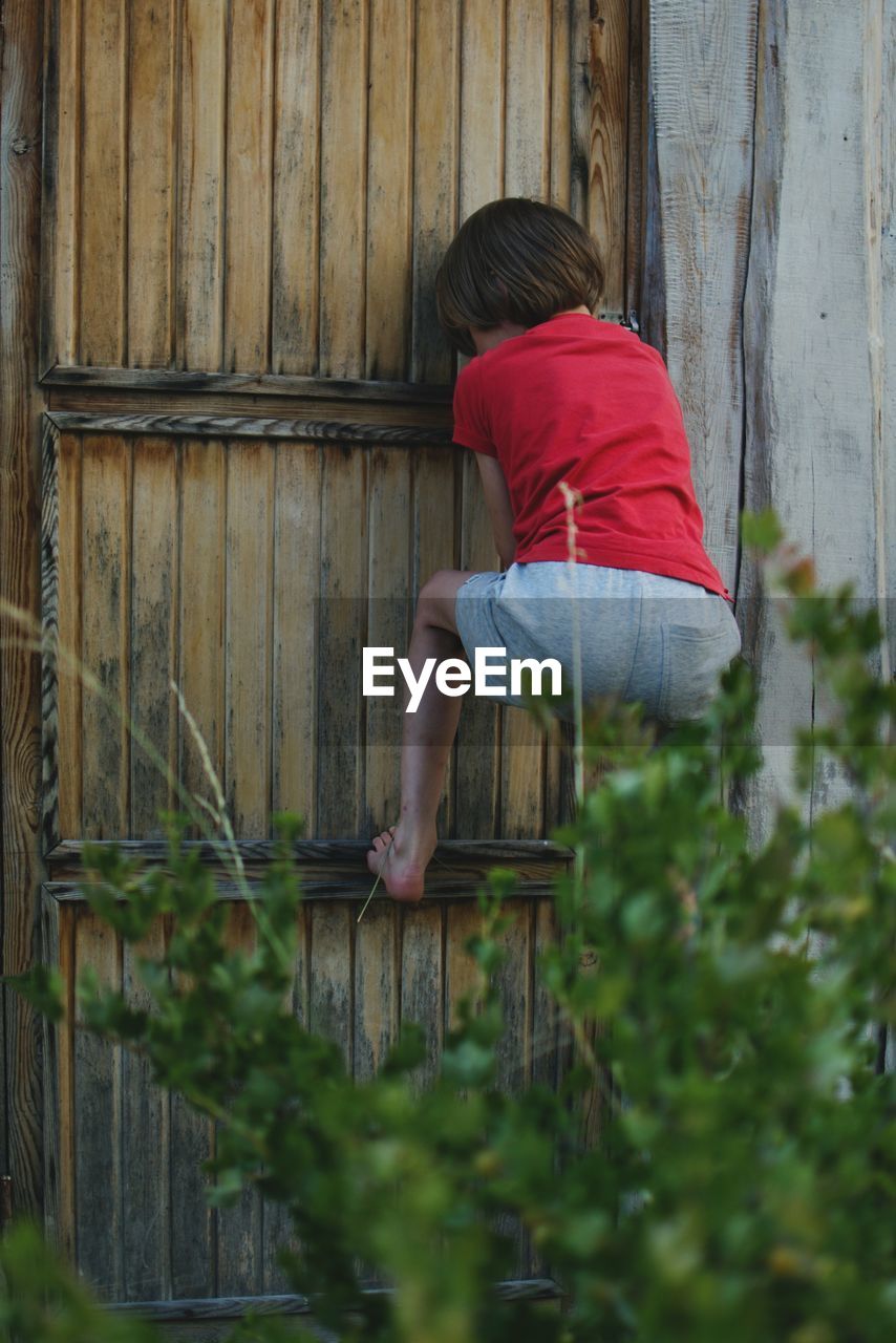 Rear view of boy climbing on fence