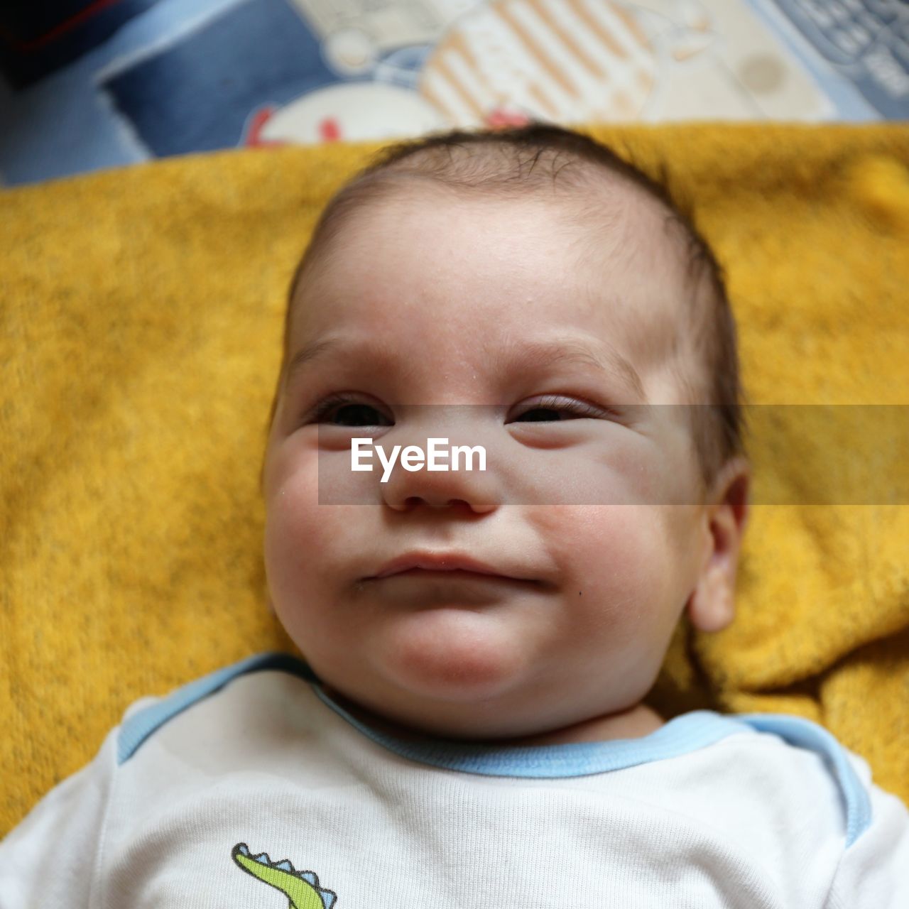 Portrait of cute baby boy lying on bed at home