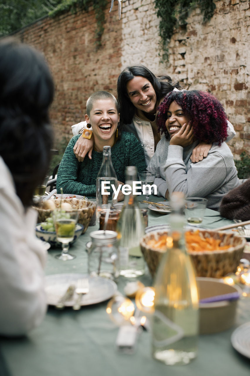 Happy female friends enjoying together at dining table during dinner party in back yard