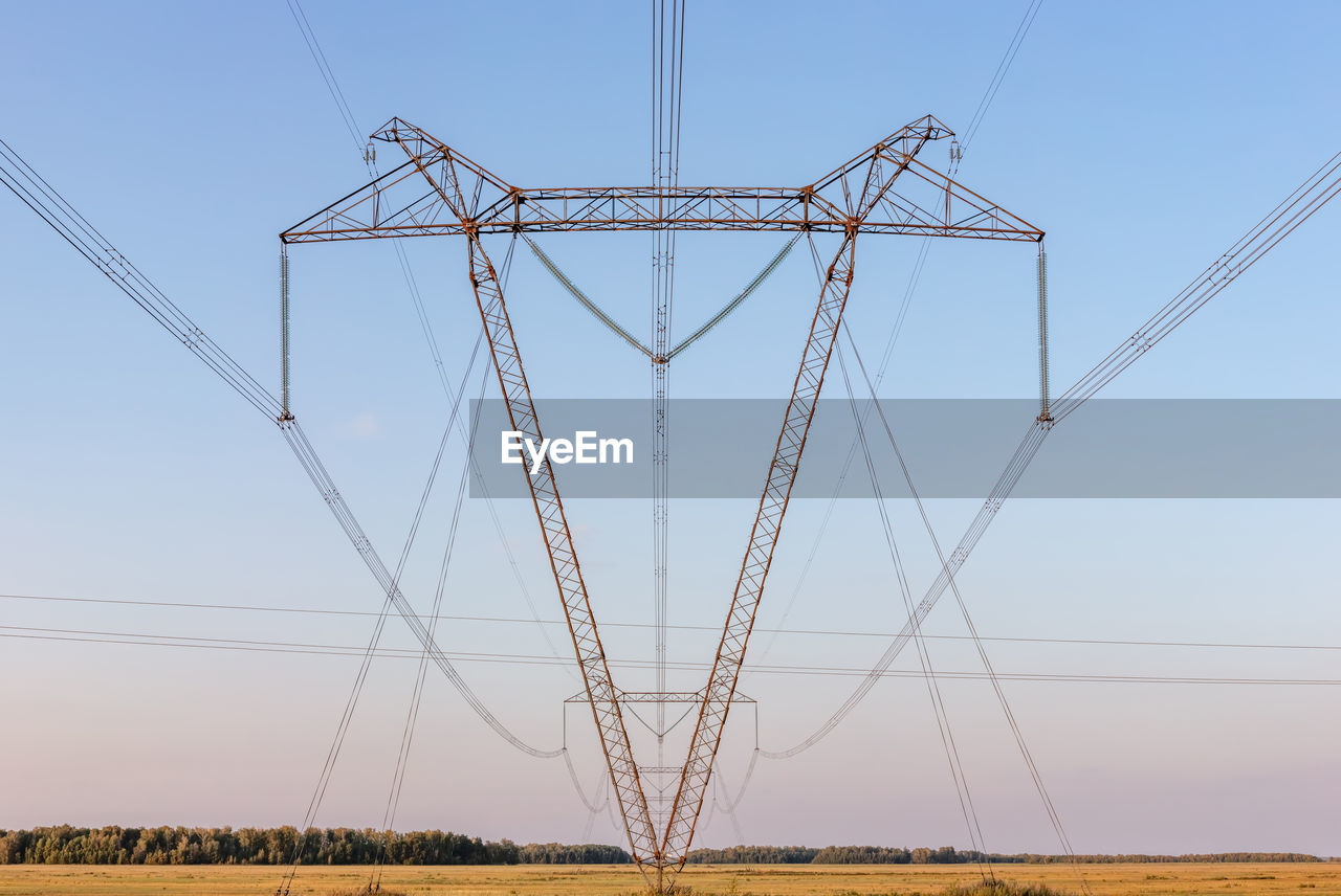 LOW ANGLE VIEW OF ELECTRICITY PYLON ON FIELD AGAINST CLEAR SKY