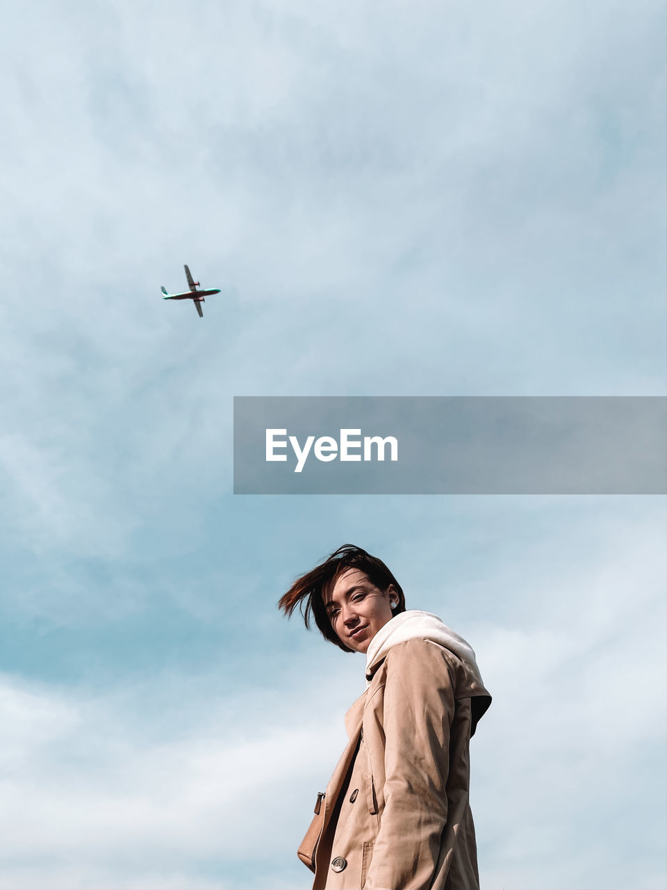 Low angle view of airplane flying against sky and girl