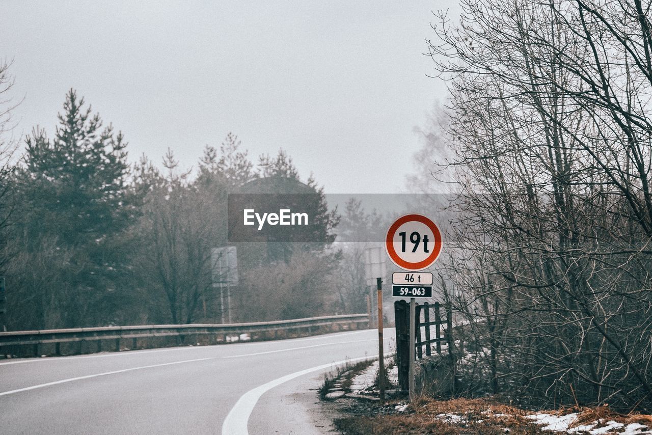 Road sign by trees during winter