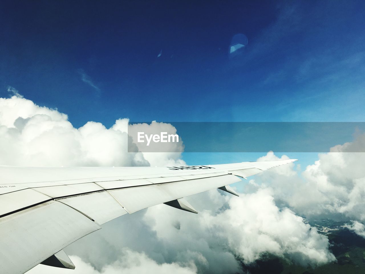 LOW ANGLE VIEW OF AIRPLANE FLYING OVER CLOUDS