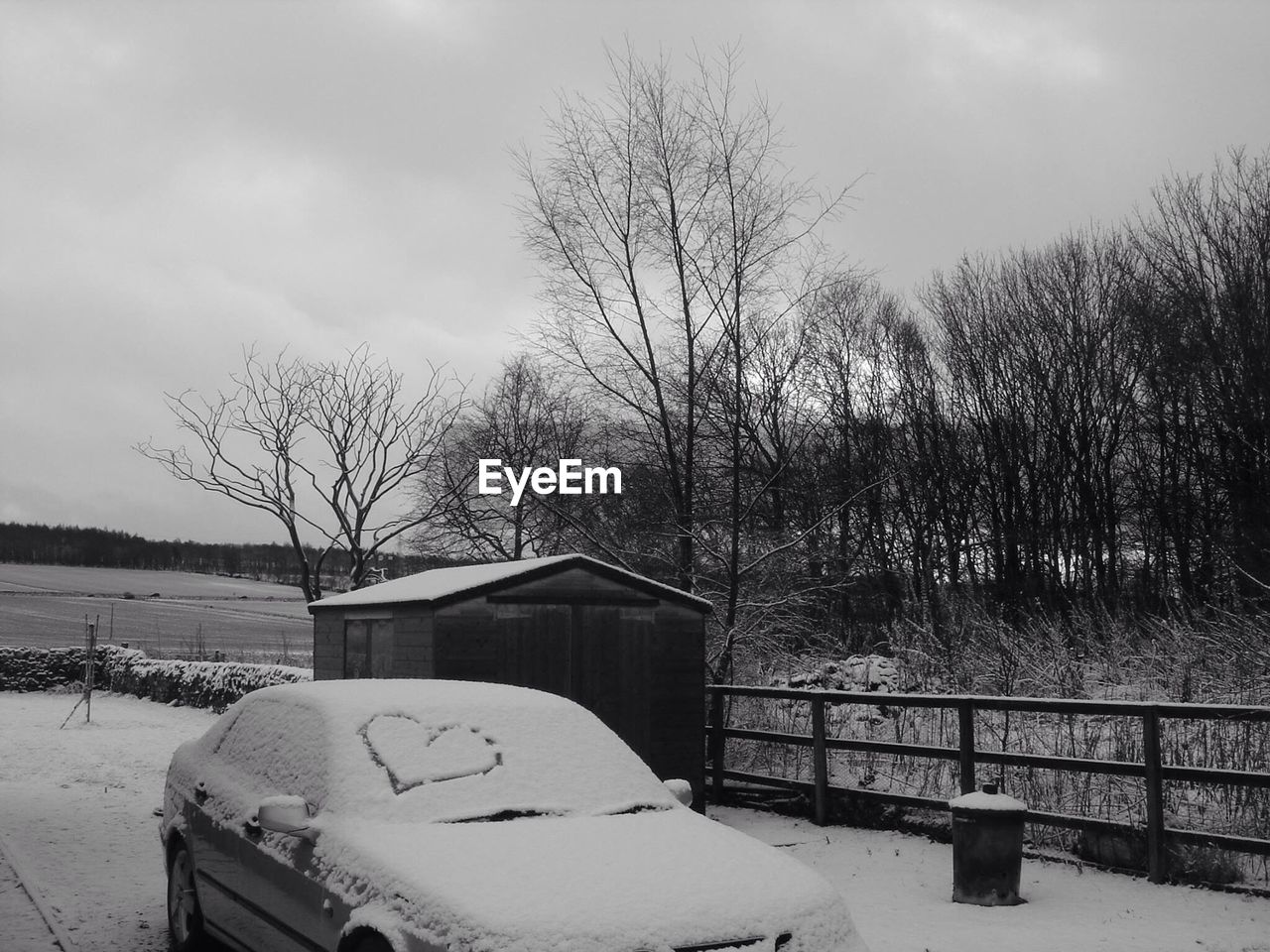 Heart shape on snow covered windshield of car